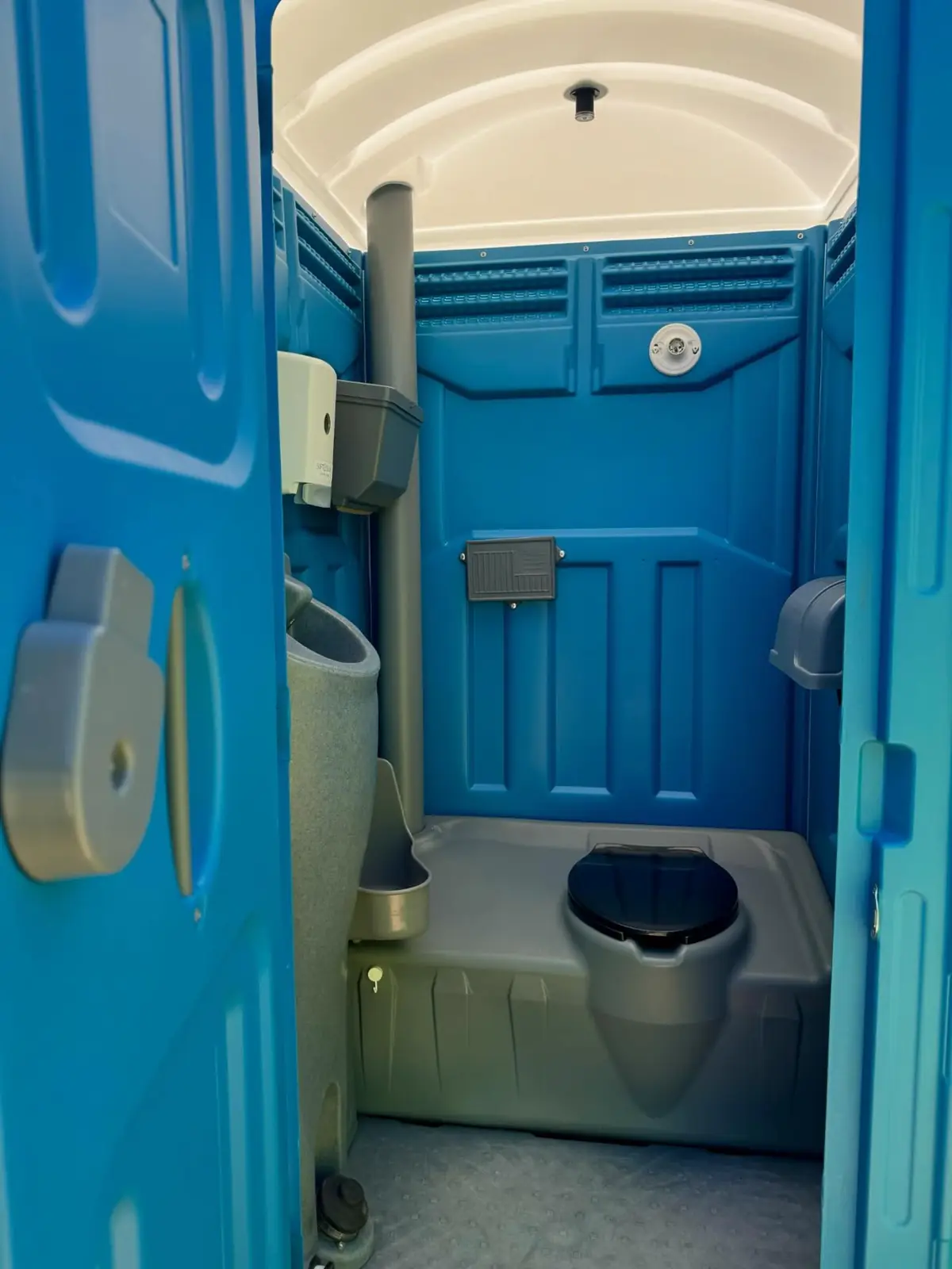 Inside a standard porta potty with seat and urinal