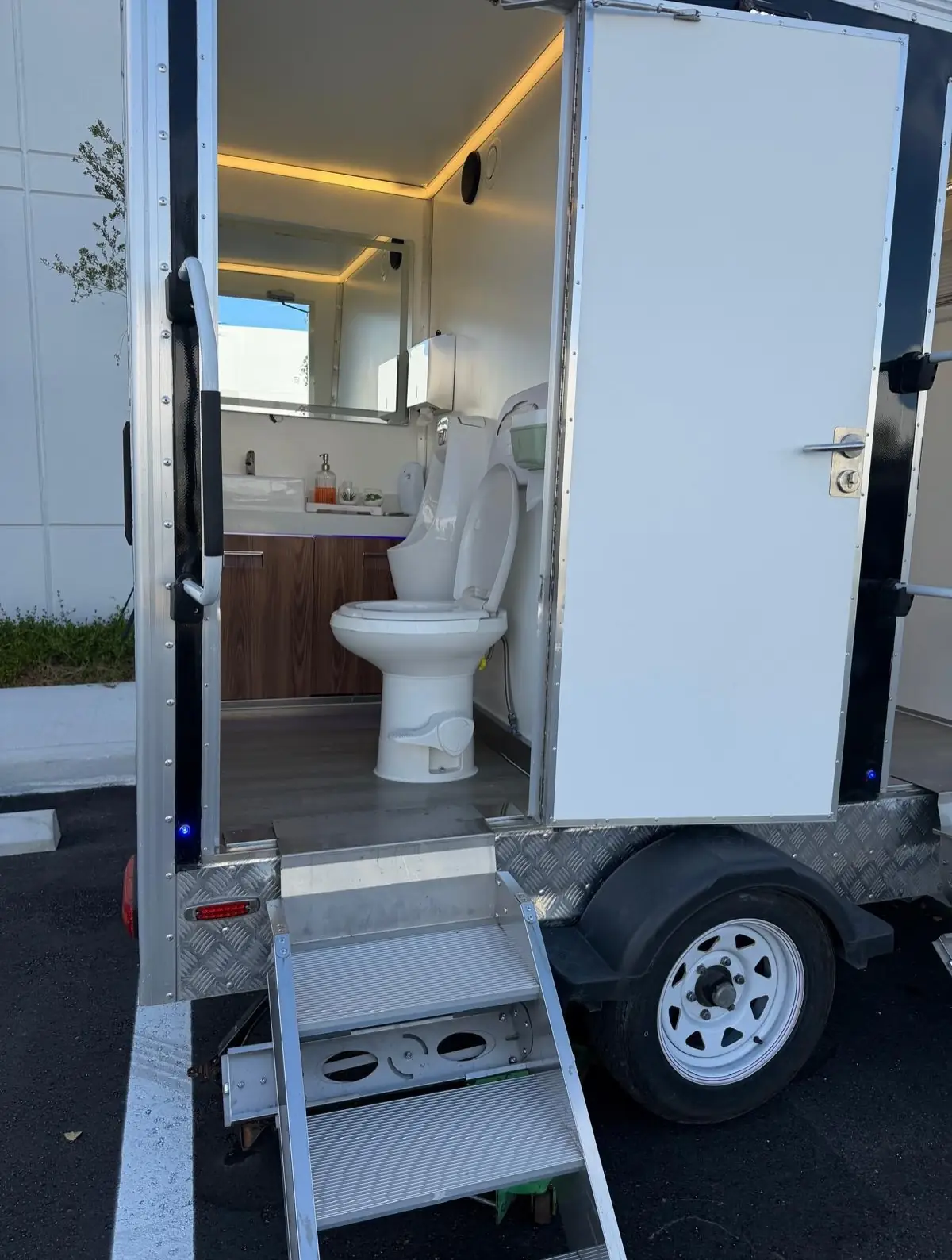 Restroom trailer interior with vanity, mirror and flushing toilet