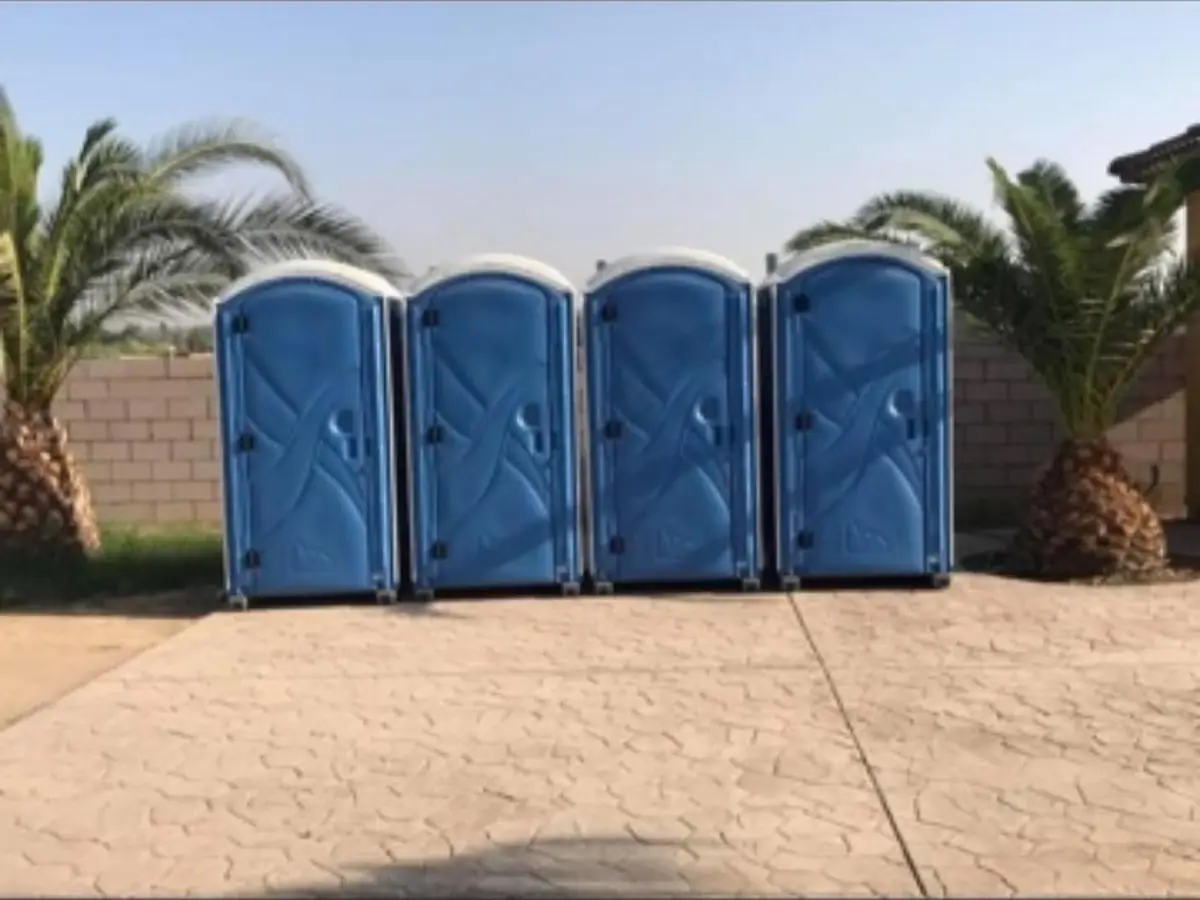 Four standard porta potties lined up on a patio