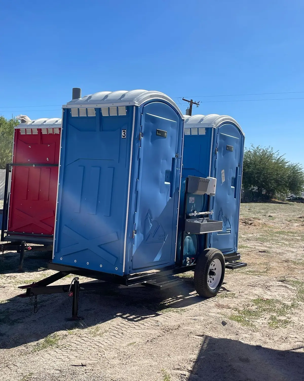 Trailer-mounted porta potty with a hand-wash sink on the side